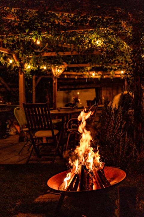 Eating area near the Eco Spa at Hill Farm Tintern at night with a fire in the fire bowl.